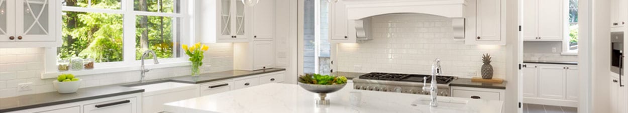 White Kitchen Interior with Island, Sink, Cabinets, and Hardwood Floors in New Luxury Home